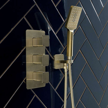 JTP Hix Twin Outlet thermostatic concealed brushed brass shower valve with vertical design and hand shower on dark tiled wall
