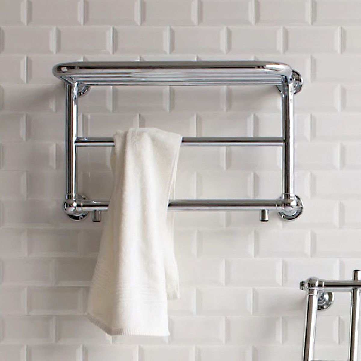 Chrome heated towel rail 400mm high x 640mm wide with warm towel hanging on white tiled bathroom wall.