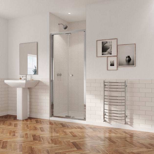 Modern bathroom featuring Coram 5mm Plain Glass chrome bi-fold shower door with clear safety glass and metal frame