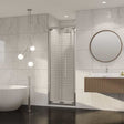 Coram 8mm plain glass chrome framed bi-fold shower door installed in modern bathroom with marble wall and round mirror
