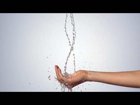 Hansgrohe Raindance Select E hand shower in matt white with water flowing onto an open hand.