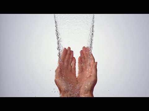 Hands under flowing water stream from Hansgrohe Raindance Shower Panel with satin chrome finish and dual jet functions.