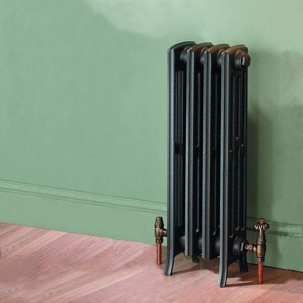 Kartel K-Rad Heritage 4 column cast iron radiator in primer finish against green wall and wooden floor