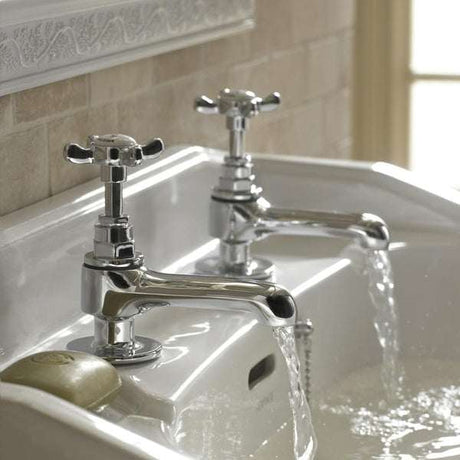 Bristan 1901 Traditional Basin Pillar Taps in chrome with ceramic disc valves installed on a white bathroom sink with water running