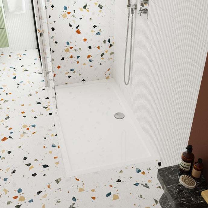 Nuie Rectangular Shower Tray Pearlstone in white installed in a modern bathroom with terrazzo tile flooring and a wall-mounted showerhead.