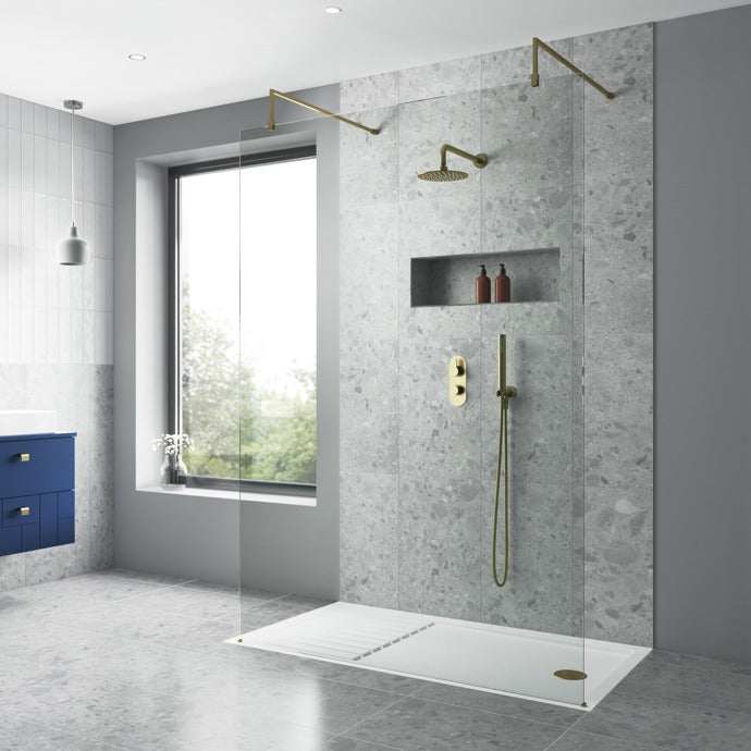 Modern bathroom shower featuring Nuie Arvan Diverter dual handle thermostatic concealed shower valve in brushed brass with matching showerhead and hand shower on gray stone wall